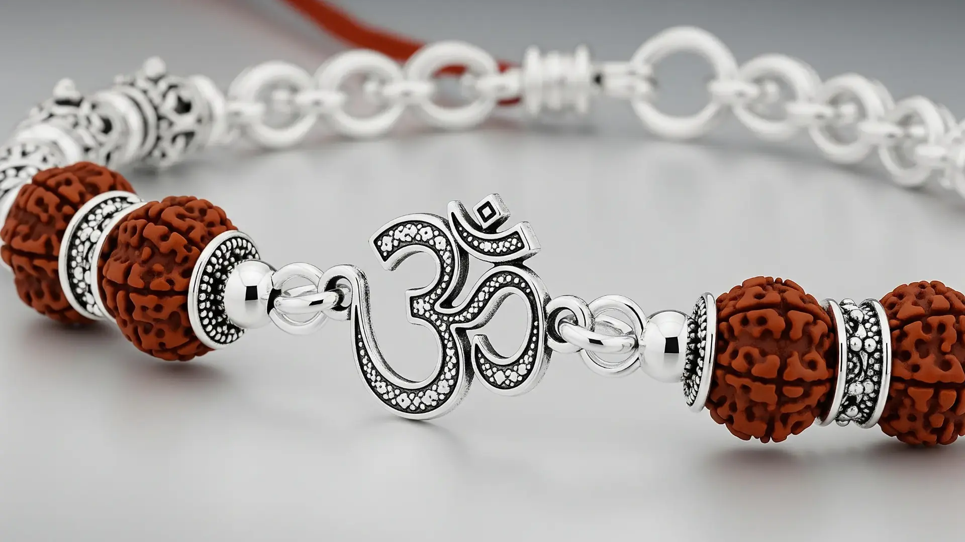 A close-up of a sleek silver bracelet Rakhi featuring a sparkling Om symbol and traditional Rudraksha beads, blending spiritual significance with modern, wearable design.
